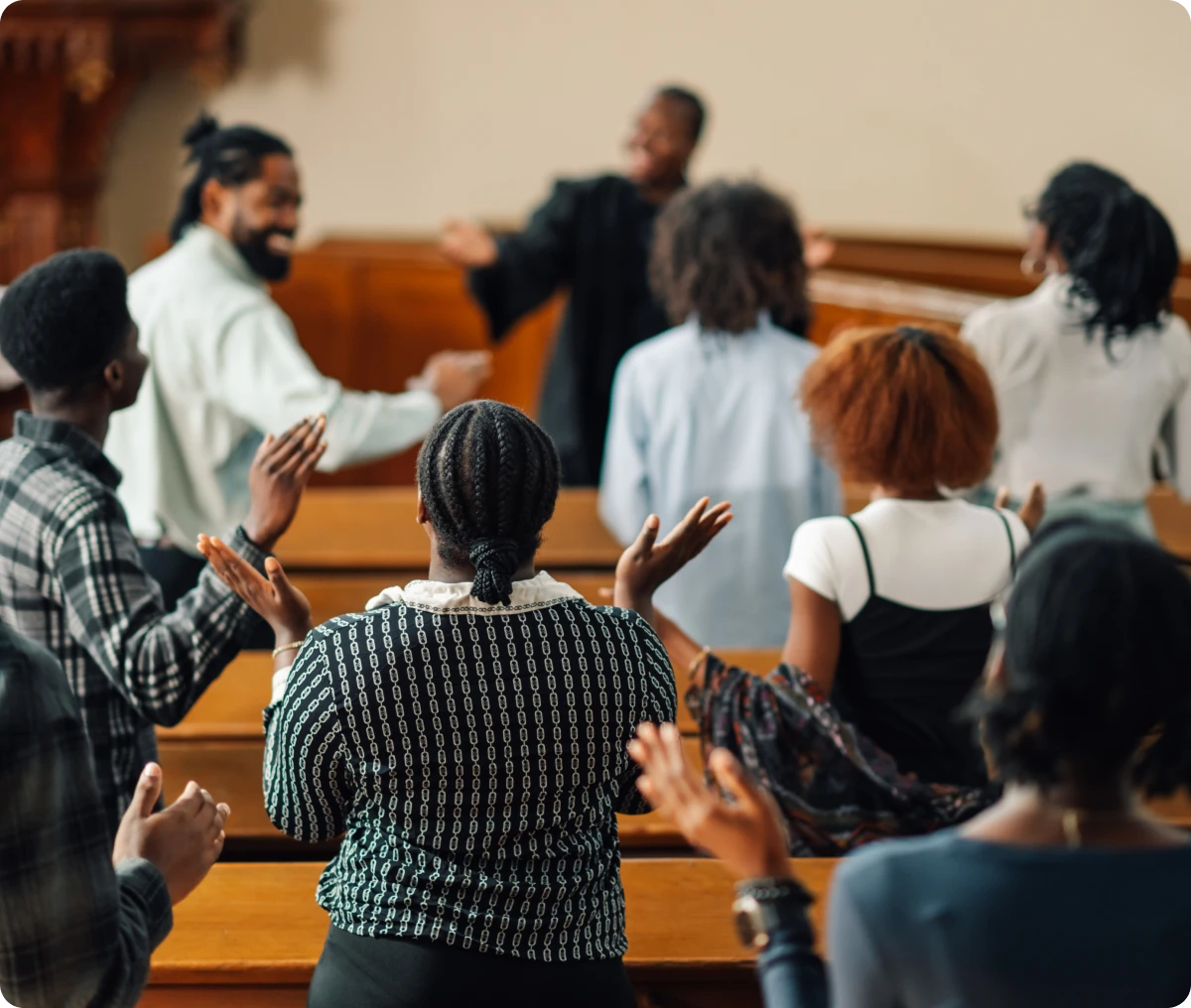 People standing in a church, clapping hands.